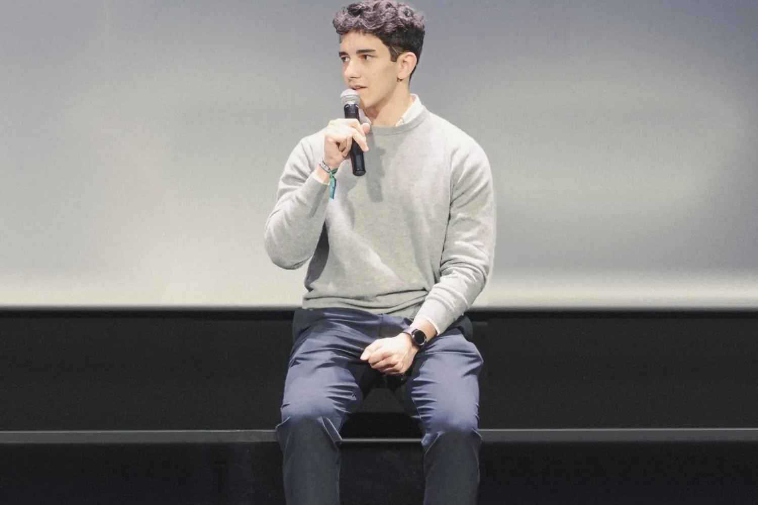 Tomás Olivera, micrófono en mano, hablando sentado en el escenario de un evento